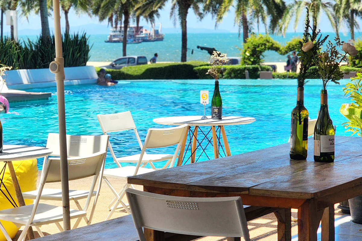 Outdoor seating with pool and ocean view at Anytime Cafe