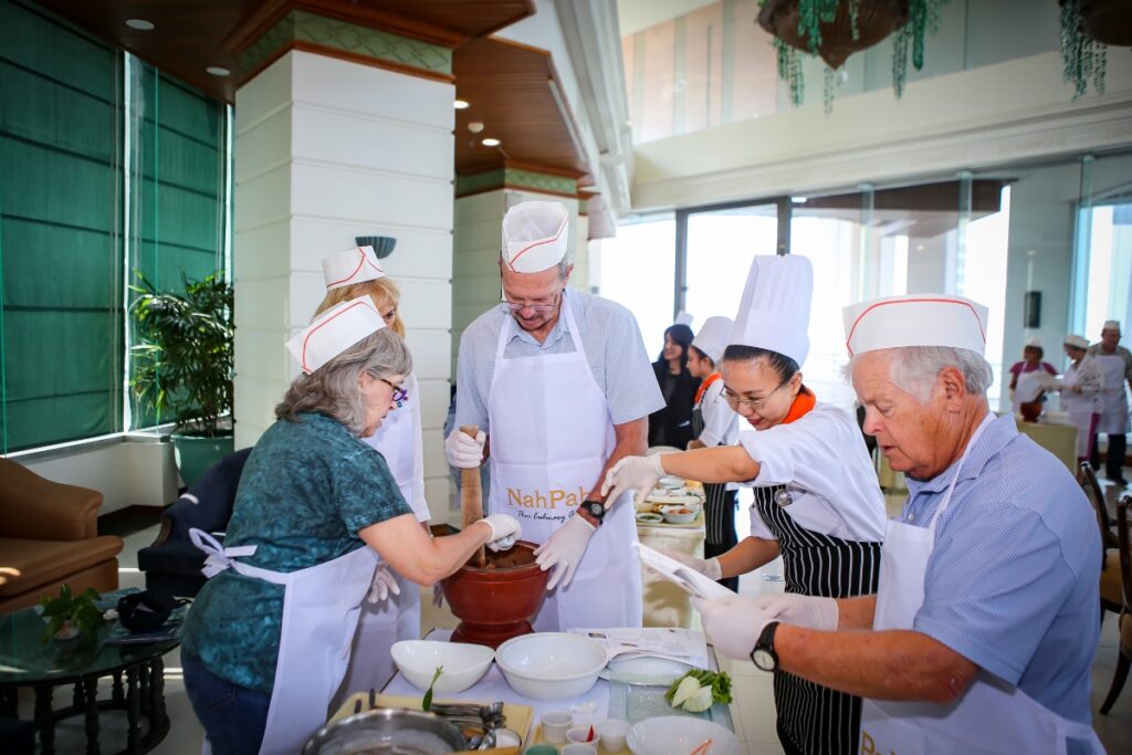 instructor teaching students how to use mortar and pestle to make thai food
